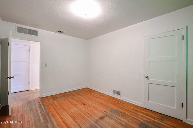 unfurnished room with a textured ceiling and hardwood / wood-style flooring