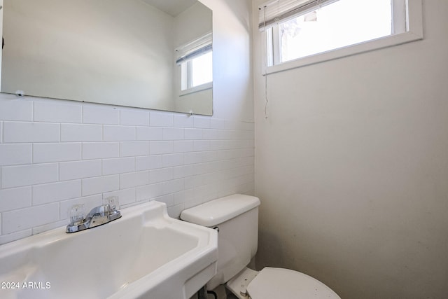 bathroom featuring toilet, sink, and tile walls