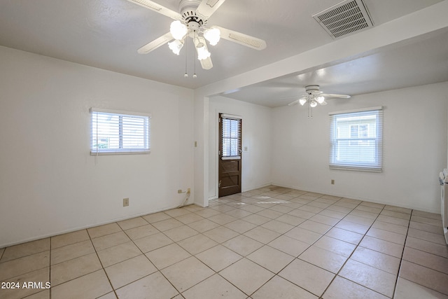 empty room featuring light tile patterned floors, a healthy amount of sunlight, and ceiling fan