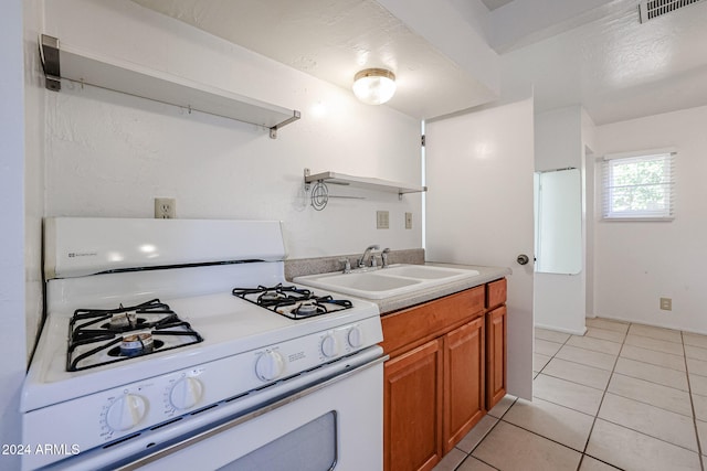 kitchen with sink, white gas range oven, and light tile patterned flooring