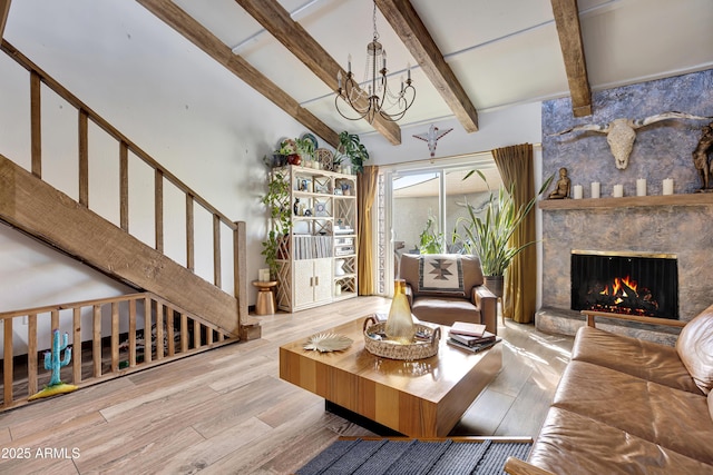 living room featuring a large fireplace, beamed ceiling, wood finished floors, a notable chandelier, and high vaulted ceiling