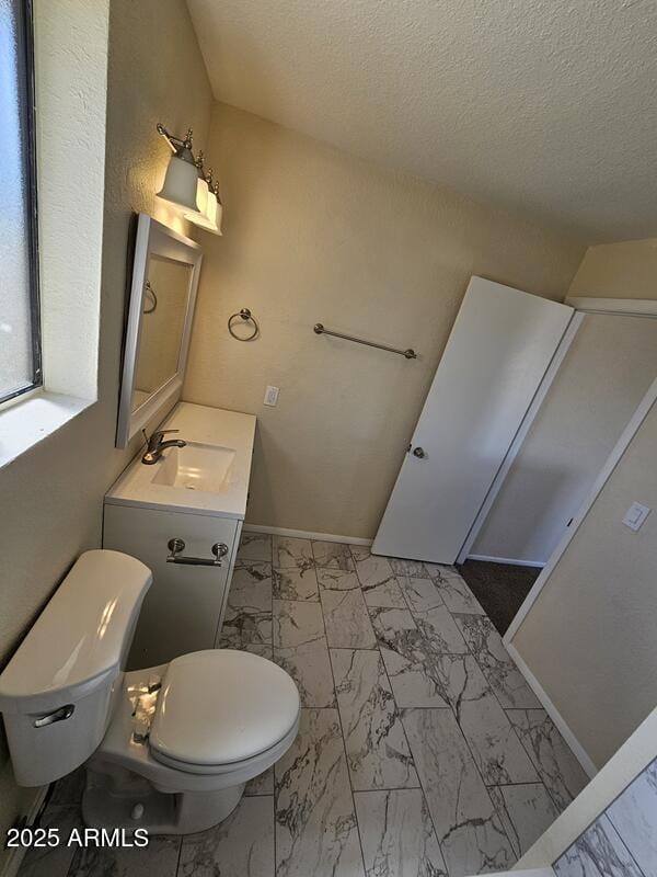 bathroom featuring toilet, marble finish floor, baseboards, and vanity