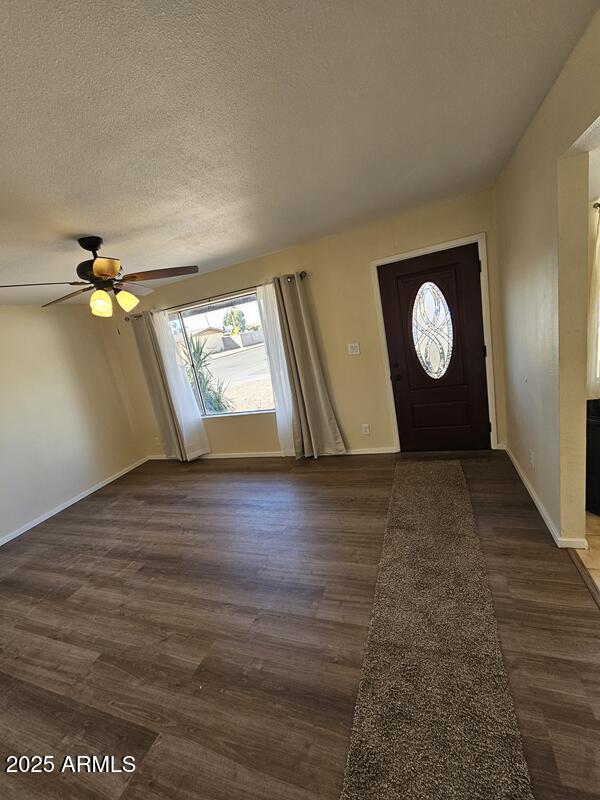 entrance foyer with a textured ceiling, dark wood finished floors, a ceiling fan, and baseboards