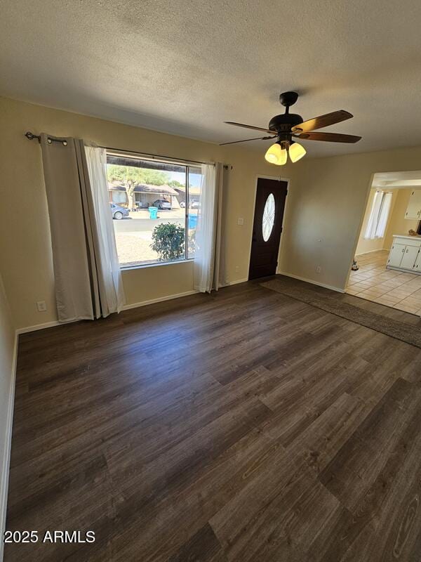 foyer featuring a ceiling fan, a textured ceiling, baseboards, and wood finished floors