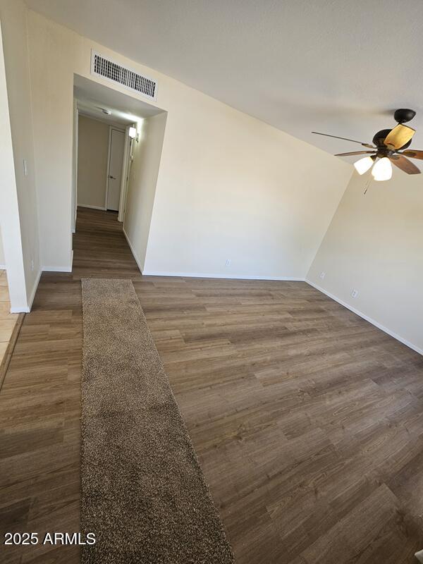 spare room featuring baseboards, ceiling fan, visible vents, and wood finished floors