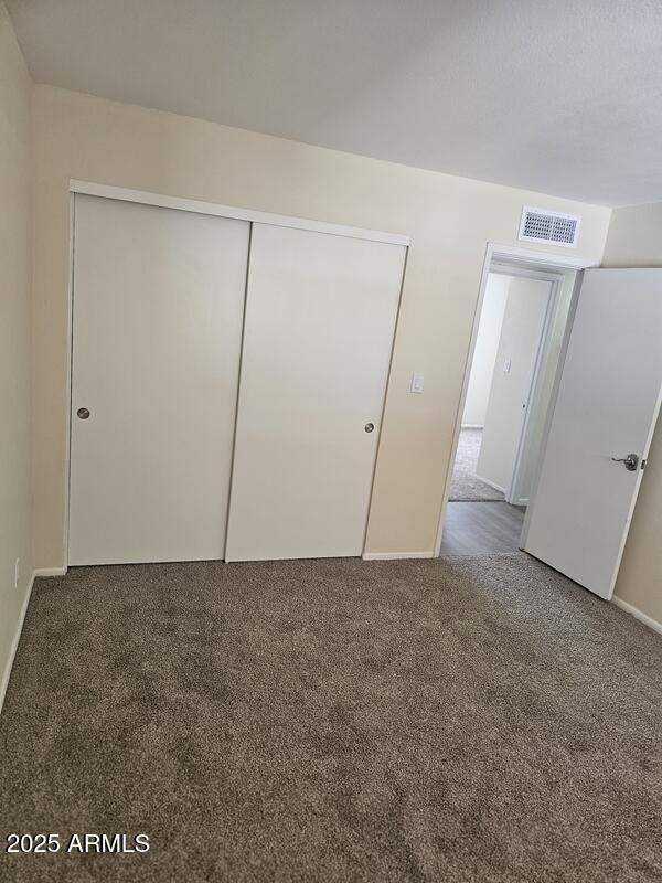 unfurnished bedroom featuring baseboards, carpet, visible vents, and a closet