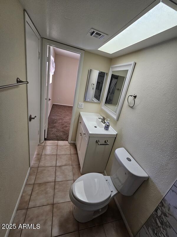 bathroom featuring tile patterned flooring, toilet, vanity, visible vents, and baseboards