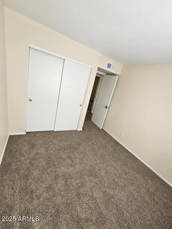 unfurnished bedroom with a closet, carpet flooring, visible vents, and baseboards