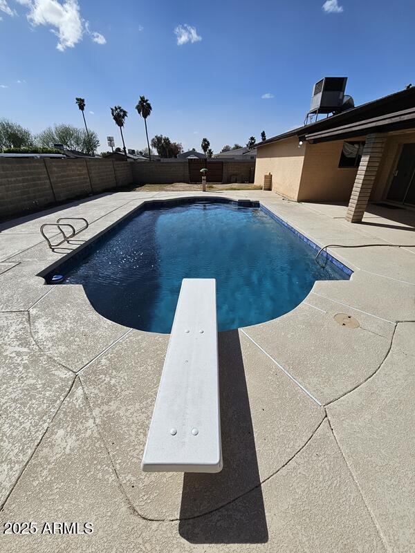 view of swimming pool featuring a fenced in pool, a fenced backyard, central air condition unit, a patio area, and a diving board