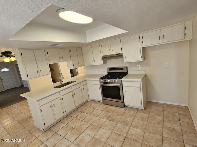 kitchen with stainless steel gas range oven, ceiling fan, light countertops, under cabinet range hood, and a sink