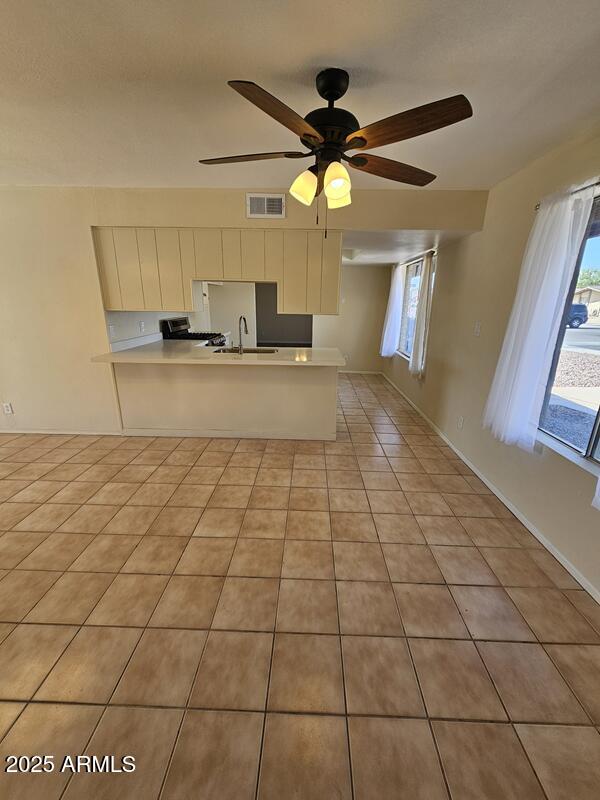 kitchen with light countertops, visible vents, a peninsula, and light tile patterned floors