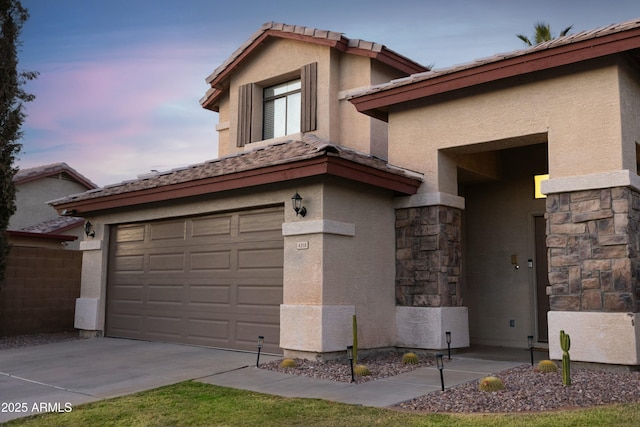 view of front of property with a garage, driveway, stone siding, a tiled roof, and stucco siding