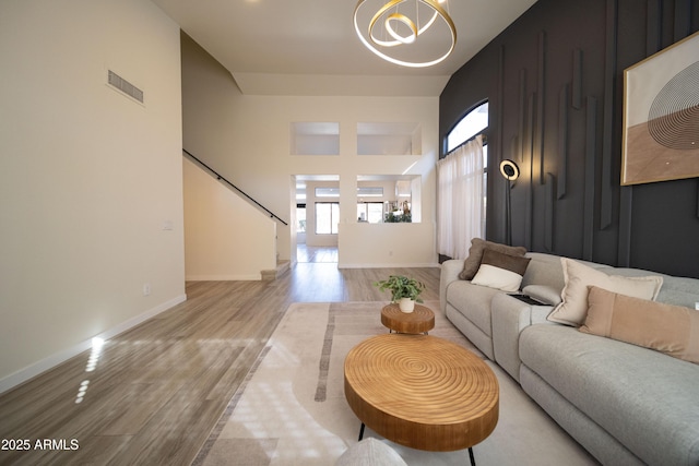 living room with a towering ceiling, an inviting chandelier, and light hardwood / wood-style flooring