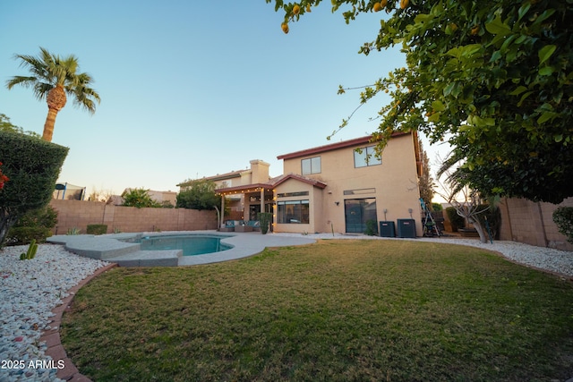 back of house with central AC unit, a fenced in pool, a fenced backyard, a yard, and stucco siding