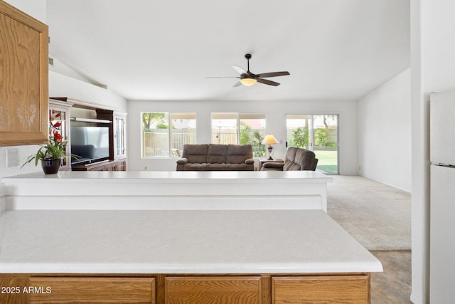 kitchen featuring lofted ceiling, a ceiling fan, healthy amount of natural light, freestanding refrigerator, and light colored carpet