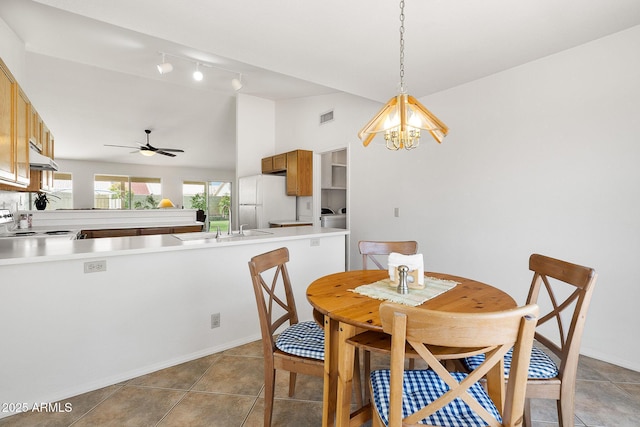 dining room with a chandelier, vaulted ceiling, light tile patterned floors, a ceiling fan, and baseboards