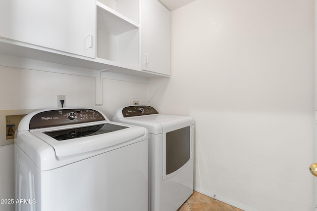 laundry room featuring washer and clothes dryer, cabinet space, baseboards, and light tile patterned floors