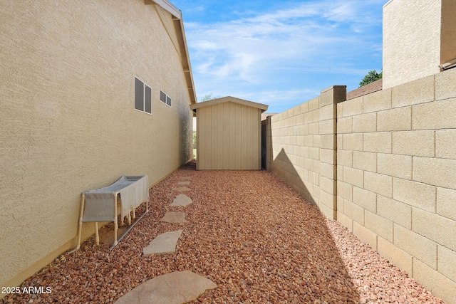 view of yard featuring fence, a storage unit, and an outbuilding