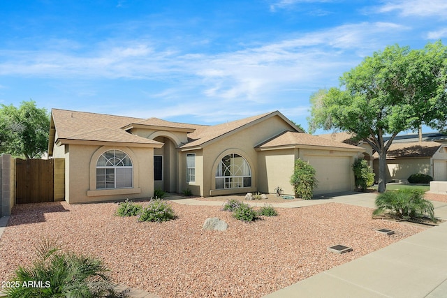 view of front of home with stucco siding, an attached garage, fence, driveway, and roof with shingles