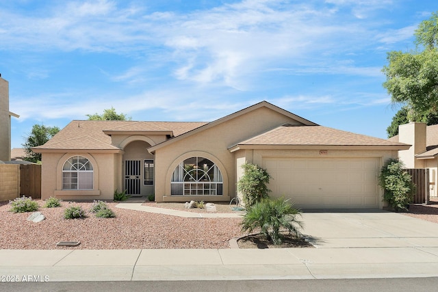 view of front facade with an attached garage, stucco siding, driveway, and fence