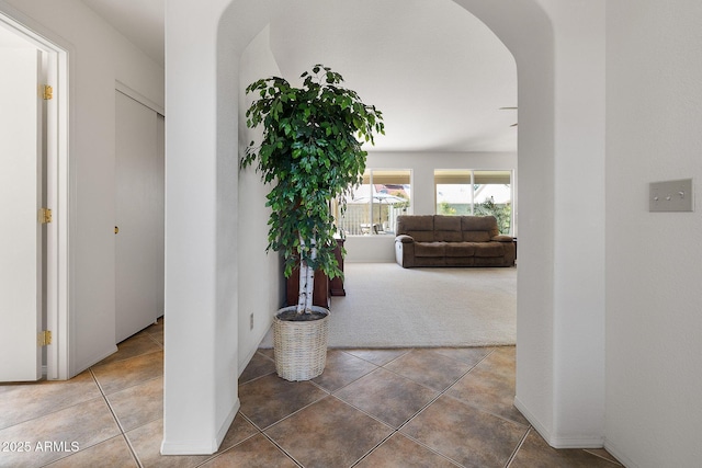 hallway with arched walkways and tile patterned floors