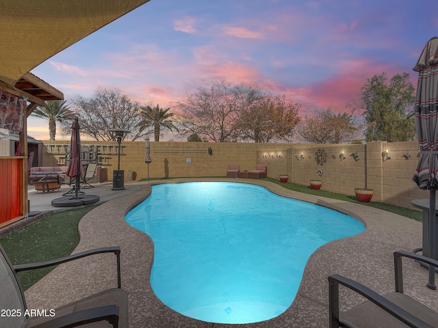 pool at dusk with an outdoor fire pit and a patio