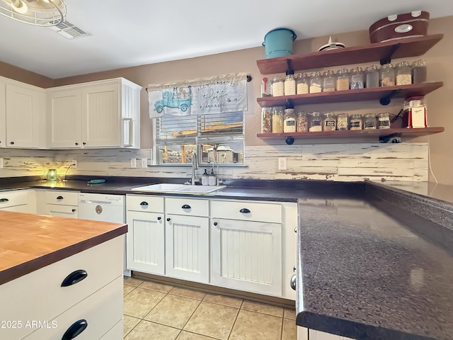 kitchen featuring dishwasher, decorative backsplash, white cabinets, light tile patterned flooring, and sink