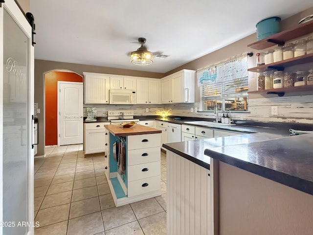 kitchen featuring sink, white cabinets, white appliances, light tile patterned flooring, and a barn door