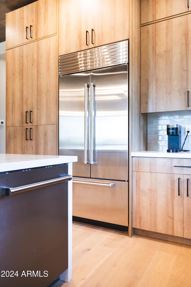 kitchen with decorative backsplash, light hardwood / wood-style floors, light brown cabinetry, and appliances with stainless steel finishes