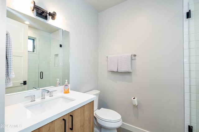 bathroom featuring a shower with door, vanity, and toilet