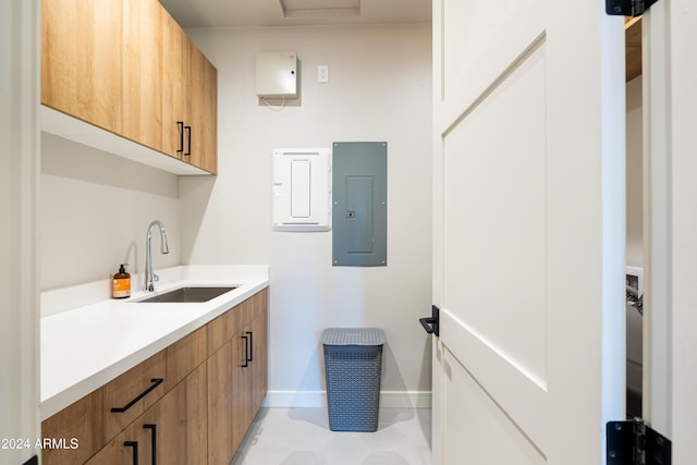 clothes washing area featuring electric panel, sink, and light tile patterned floors