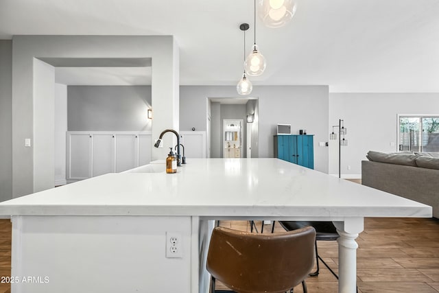 kitchen with sink, decorative light fixtures, a breakfast bar area, and hardwood / wood-style floors