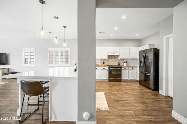 kitchen featuring white cabinetry, backsplash, a kitchen bar, hanging light fixtures, and stainless steel appliances