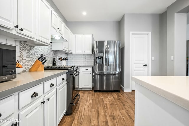 kitchen featuring stainless steel refrigerator with ice dispenser, light hardwood / wood-style flooring, black gas stove, white cabinets, and backsplash