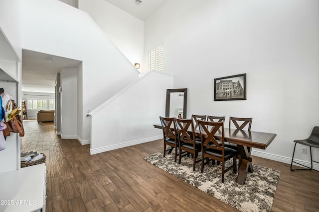 dining room with a towering ceiling and dark hardwood / wood-style flooring