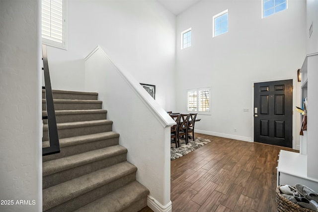 entryway with dark hardwood / wood-style flooring and a towering ceiling