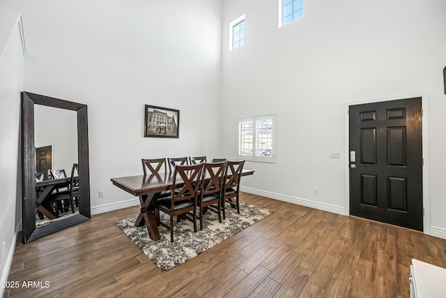 dining area featuring a towering ceiling and dark hardwood / wood-style floors