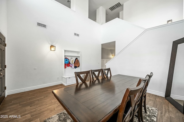 dining area with dark wood-type flooring and a towering ceiling