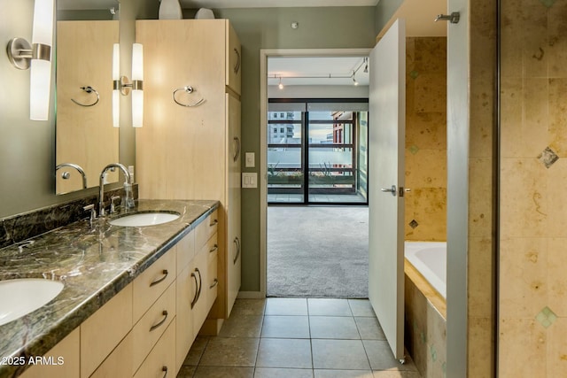 bathroom featuring tile patterned flooring, vanity, and a relaxing tiled tub