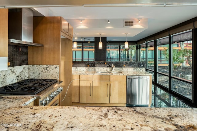 kitchen featuring light stone countertops, wall chimney range hood, stainless steel dishwasher, pendant lighting, and range