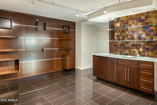 bar with dark tile patterned floors, track lighting, and sink