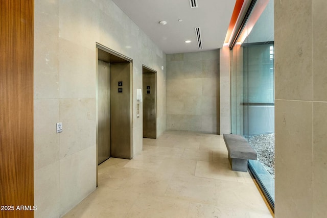 hallway featuring elevator and tile walls