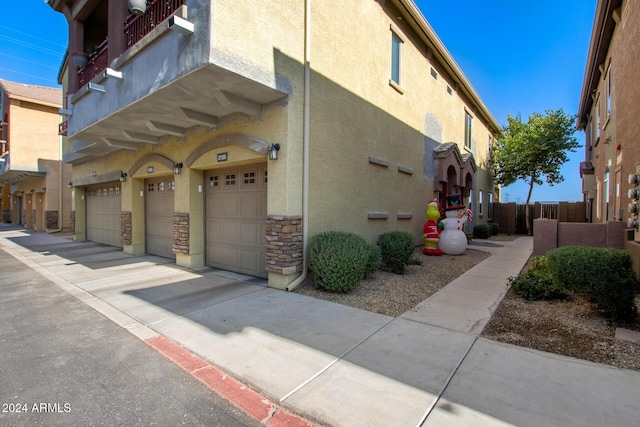 view of side of home with a garage and a balcony