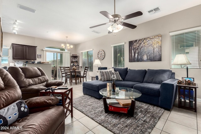 tiled living room with ceiling fan with notable chandelier