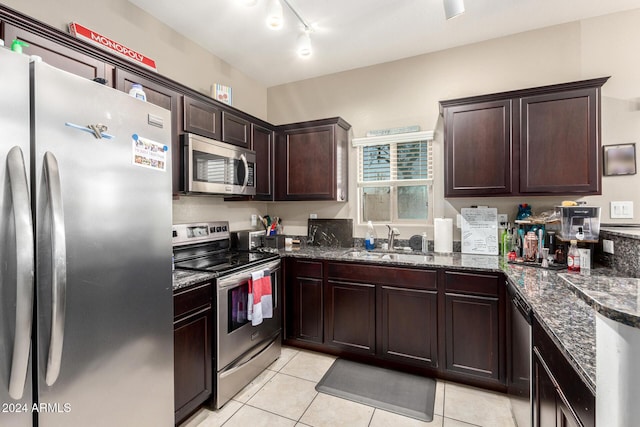 kitchen featuring light tile patterned floors, appliances with stainless steel finishes, sink, and dark stone counters