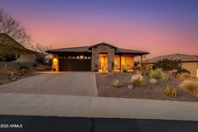 view of front of house featuring an attached garage, stone siding, driveway, and stucco siding