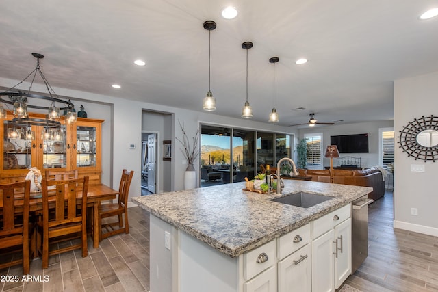 kitchen with decorative light fixtures, light wood-type flooring, light stone counters, recessed lighting, and a sink