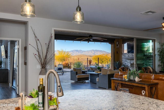 interior space featuring fence, visible vents, a sink, ceiling fan, and a mountain view