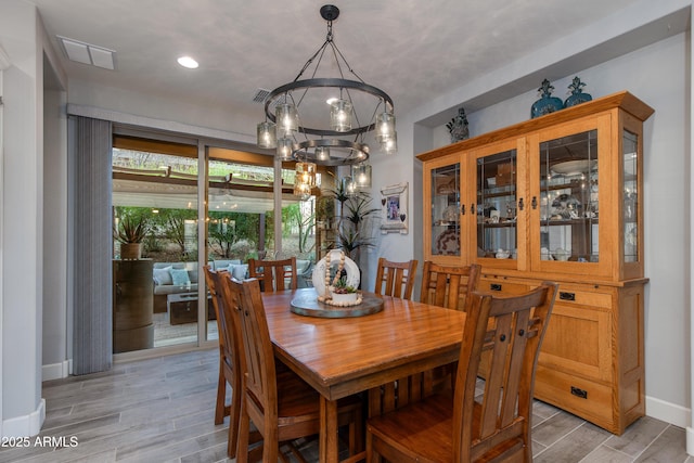 dining space featuring a notable chandelier, baseboards, visible vents, and wood tiled floor