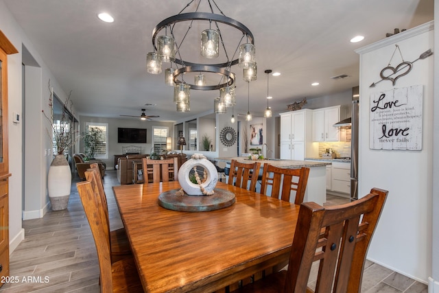 dining space featuring recessed lighting, light wood-type flooring, visible vents, and ceiling fan with notable chandelier